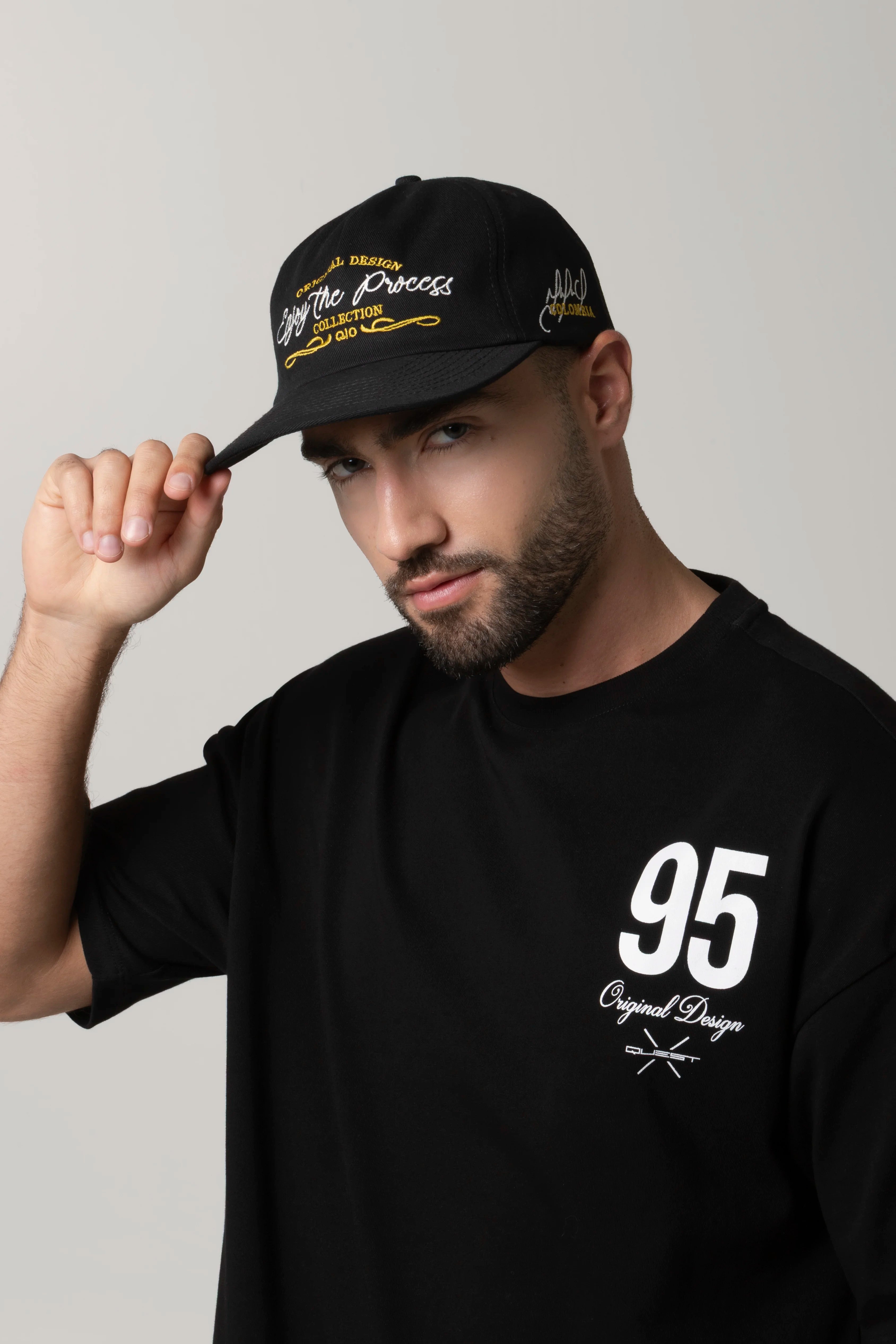 GORRA BEISBOLERA EN BLOQUES DE COLOR NEGRO CON BORDADO MARCA QUEST X JUAN FERNANDO QUINTERO