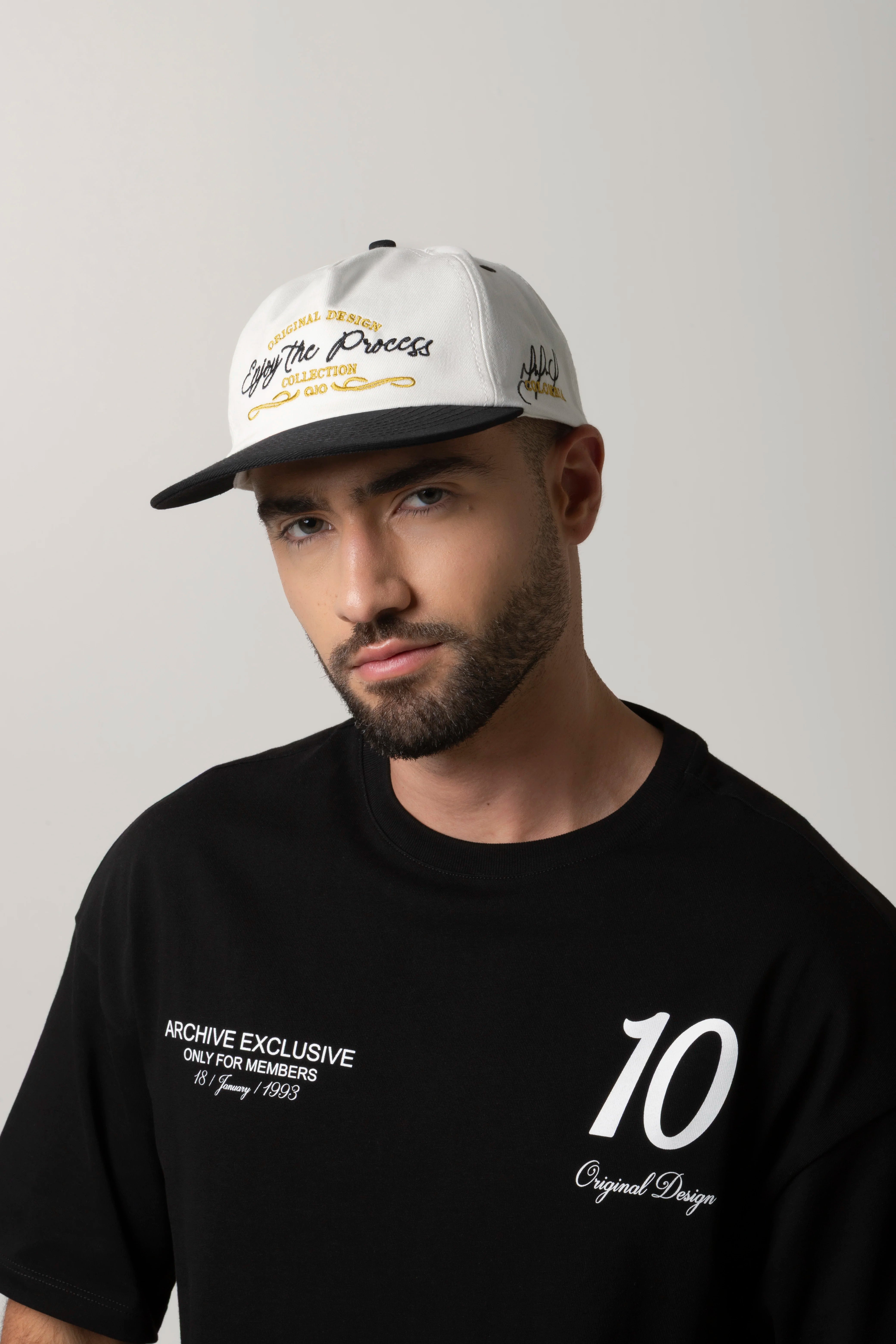 GORRA BEISBOLERA EN BLOQUES DE COLOR BEIGE CON BORDADO MARCA QUEST X JUAN FERNANDO QUINTERO