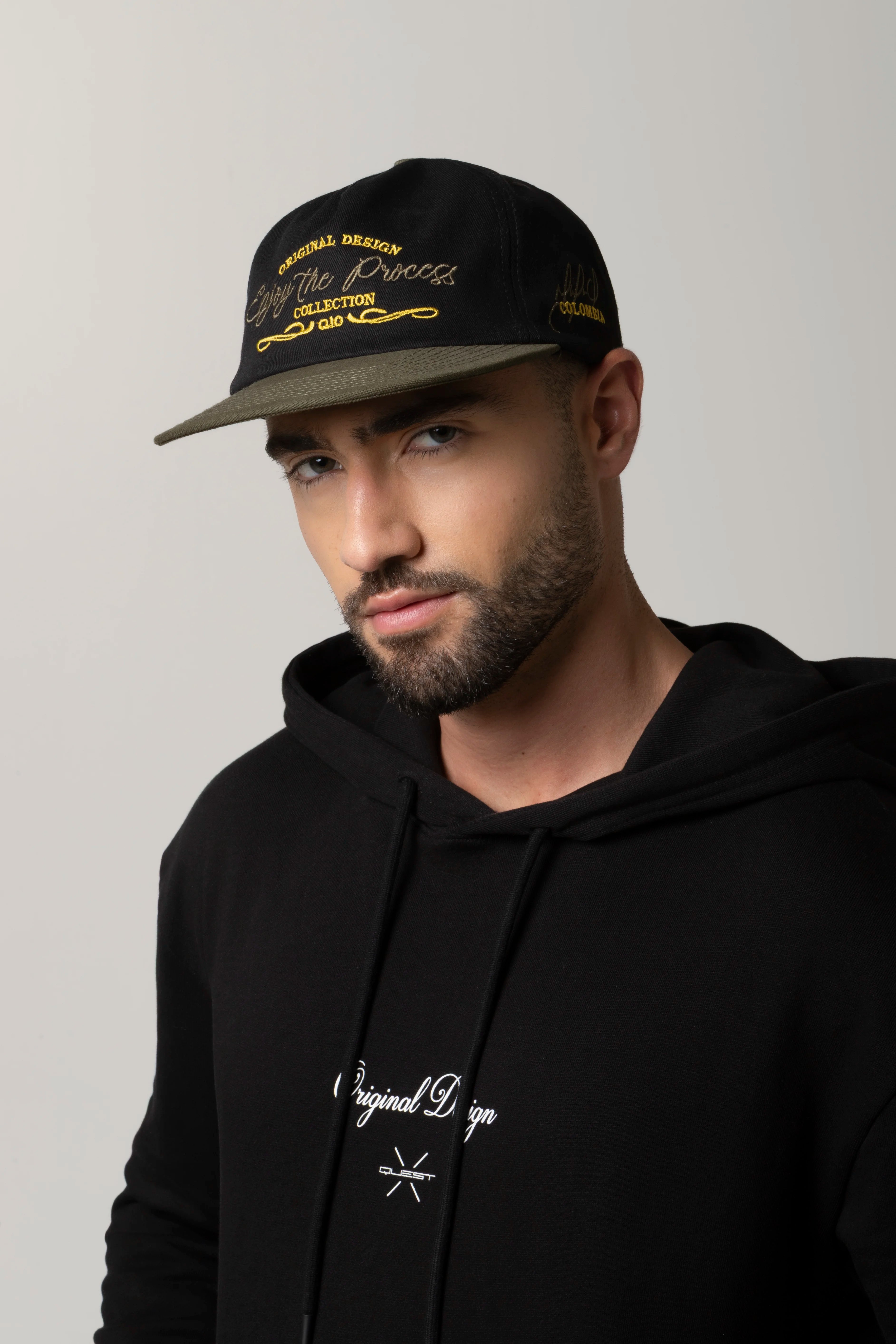 GORRA BEISBOLERA EN BLOQUES DE COLOR CON BORDADO VERDE MARCA QUEST X JUAN FERNANDO QUINTERO