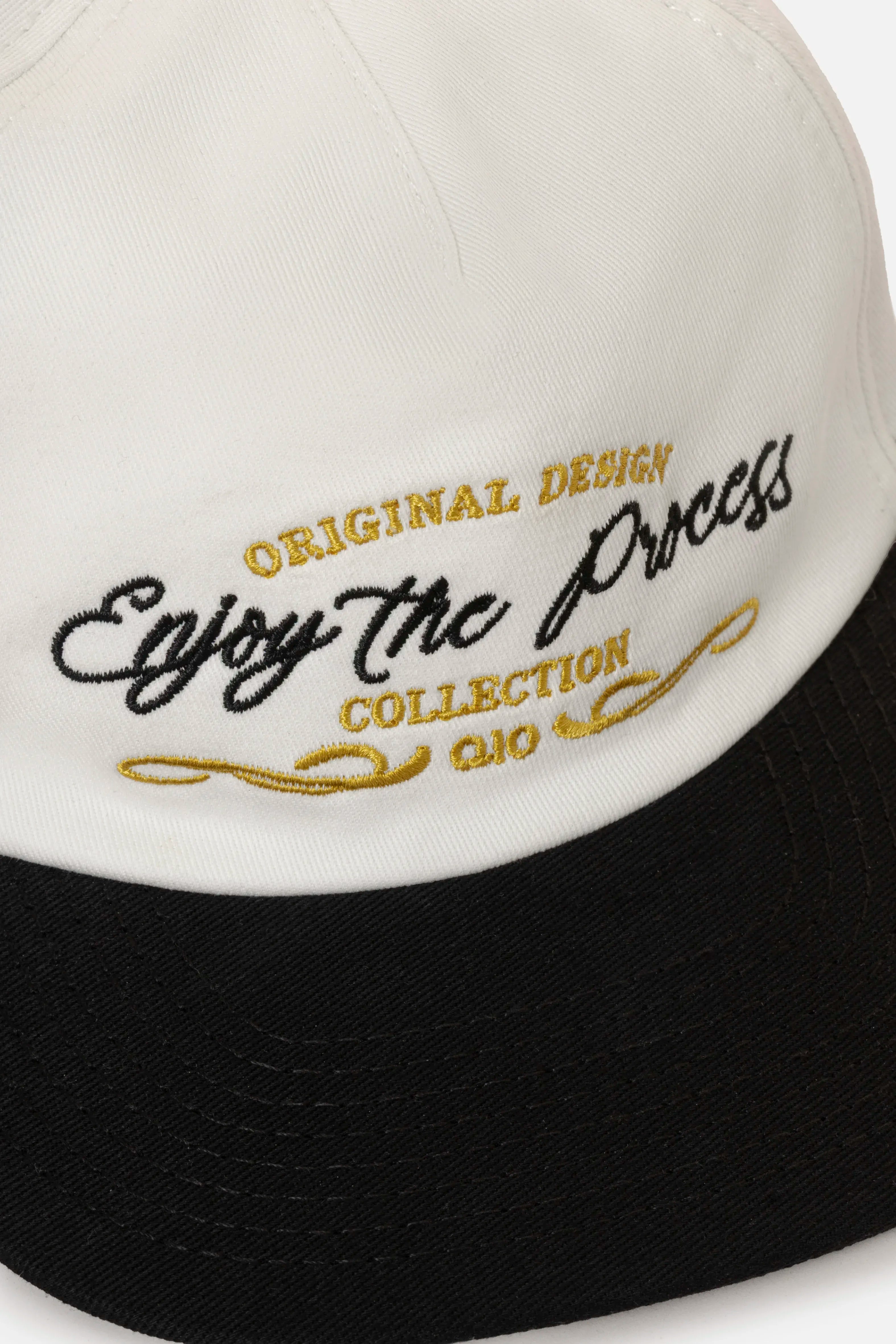 GORRA BEISBOLERA EN BLOQUES DE COLOR BEIGE CON BORDADO MARCA QUEST X JUAN FERNANDO QUINTERO