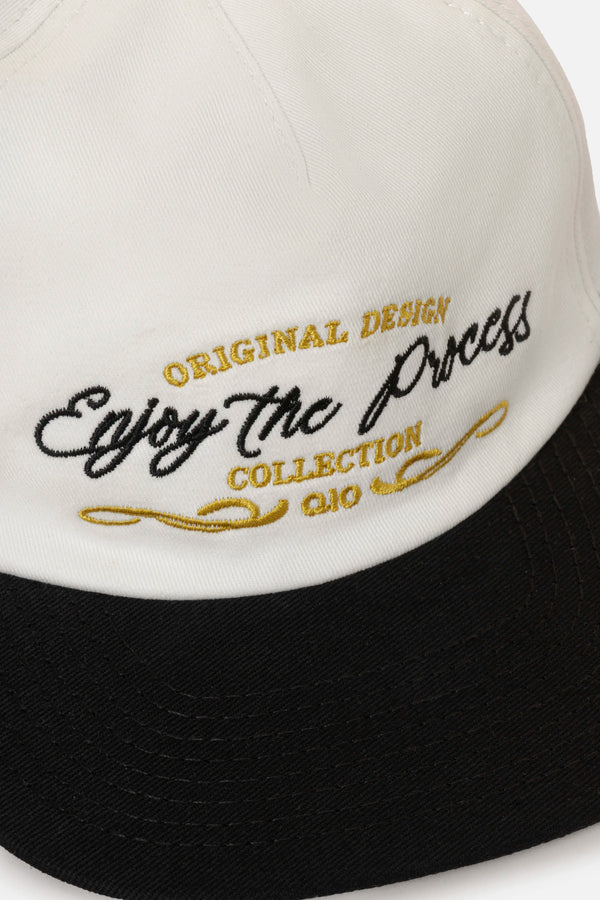 GORRA BEISBOLERA EN BLOQUES DE COLOR BEIGE CON BORDADO MARCA QUEST X JUAN FERNANDO QUINTERO