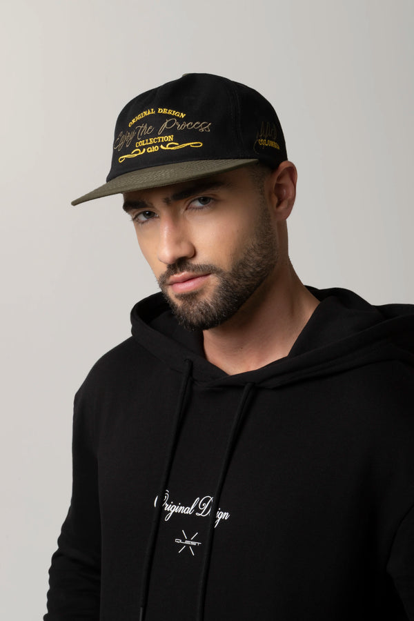 GORRA BEISBOLERA EN BLOQUES DE COLOR CON BORDADO VERDE MARCA QUEST X JUAN FERNANDO QUINTERO